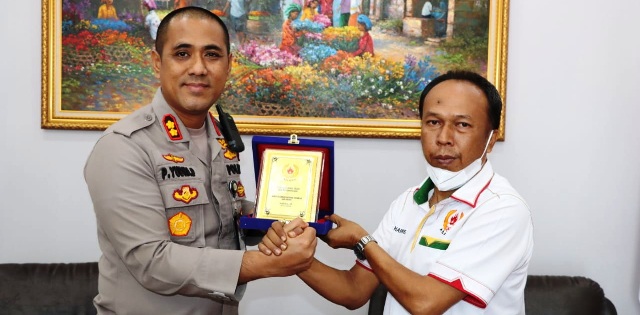 Kapolres Asahan, AKBP Putu Yudha Prawira menerima cenderamata dari Ketua KONI Kabupaten Asahan, Harris.